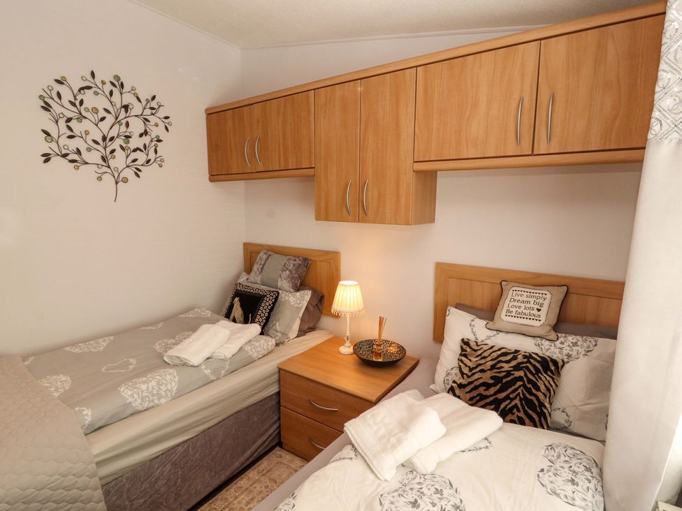 A bedroom with two beds and a nightstand at Jodene Lodge, Redwood 2, Bowness-On-Windermere