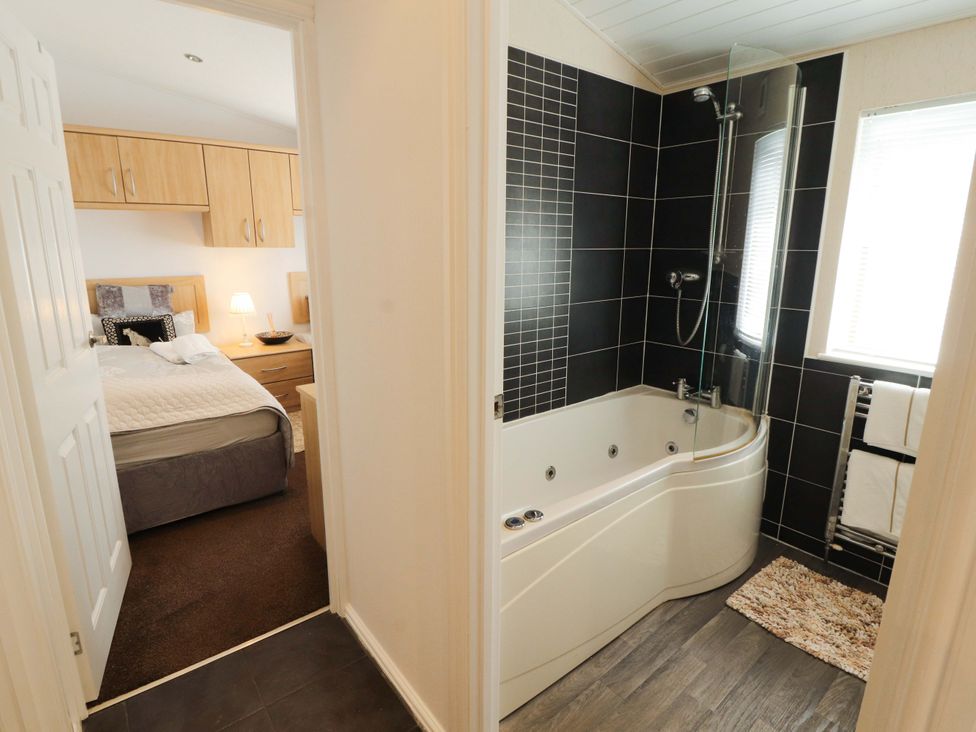 A bathroom with a bathtub and shower at Jodene Lodge, Redwood 2, Bowness-On-Windermere