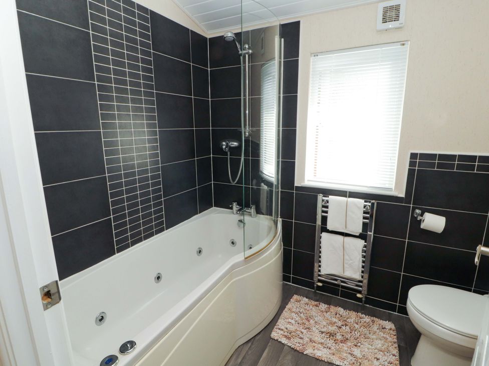 A bathroom with a bathtub and shower at Jodene Lodge, Redwood 2, Bowness-On-Windermere