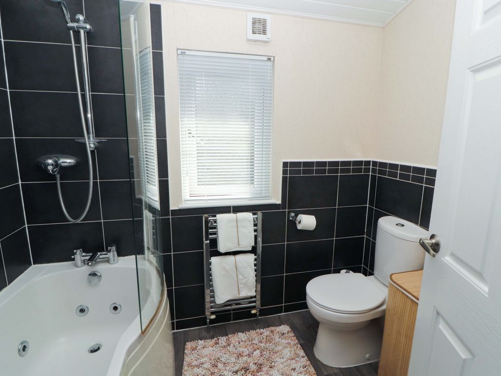 A bathroom with a shower, bathtub, and towel rack at Jodene Lodge, Redwood 2 Bowness-On-Windermere