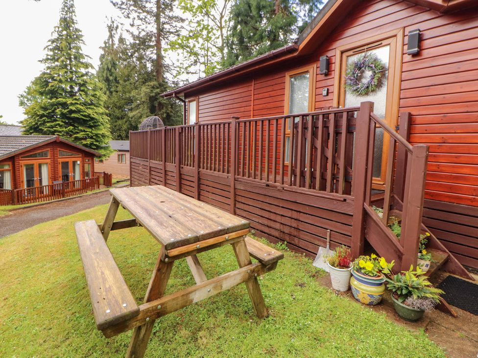 A wooden picnic table and flower pots outside a cabin at Jodene Lodge, Redwood 2 Bowness-On-Windermere