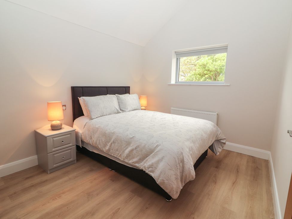 A bedroom with a bed and nightstand at 17 ROOSKA, Lisdoonvarna, County Clare
