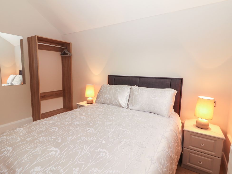 A bedroom with a bed, nightstand, and wardrobe at 17 ROOSKA, Lisdoonvarna, County Clare