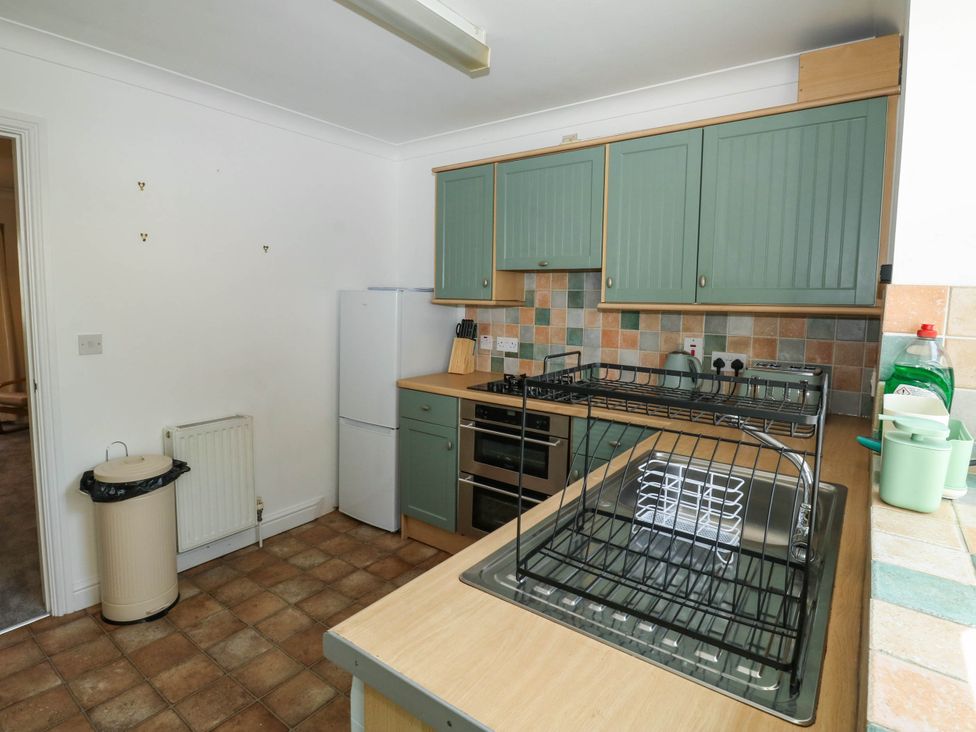 A kitchen with cabinets, a sink, a refrigerator, and a dish rack at Flat 1 in Kingsteignton