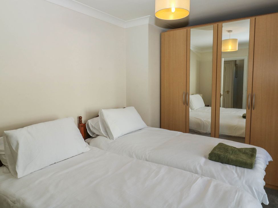 A bedroom with two single beds and a wardrobe at Flat 1 in Kingsteignton