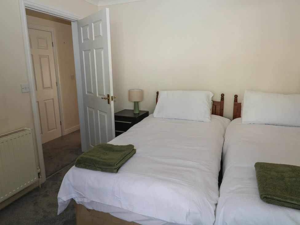 A bedroom with two single beds and a lamp at Flat 1 in Kingsteignton