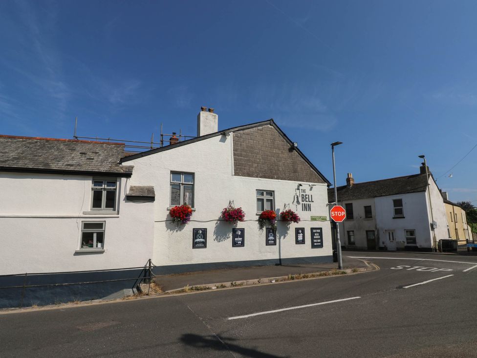 Exterior view of The Bell Inn with flower baskets and a stop sign in Kingsteignton