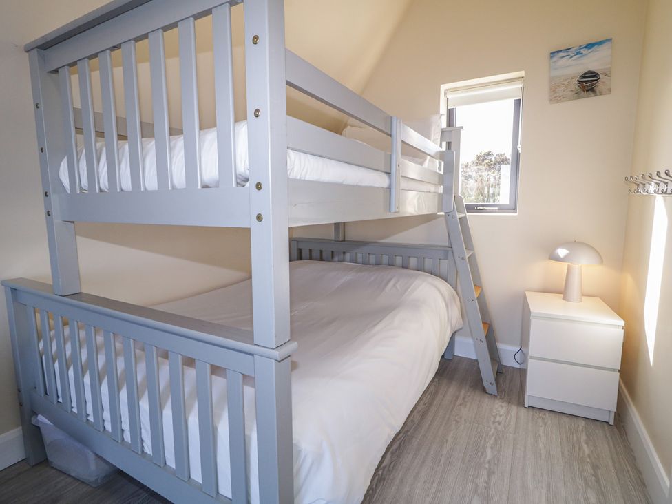 A bunk bed and nightstand with a lamp in a bedroom at Cabin 1 Machaire Rabhartaigh near Gortahork, County Donegal