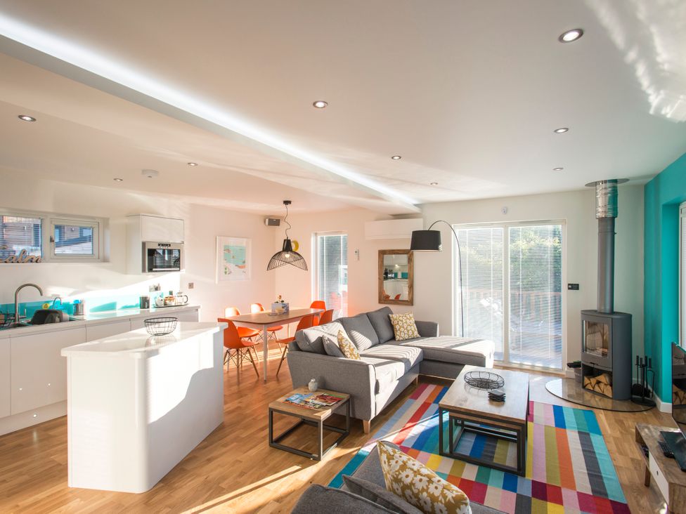 A living room with a sofa, dining table, and kitchen counter at Barbara in Portreath