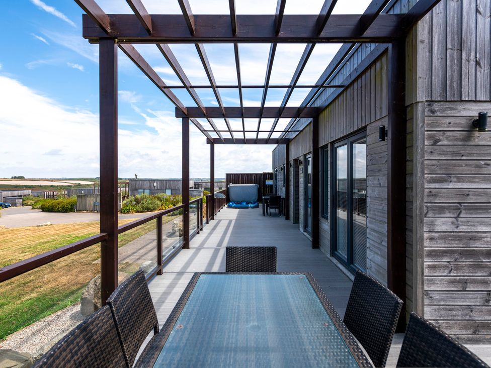 An outdoor area with a table and chairs under a pergola at Barbara in Portreath