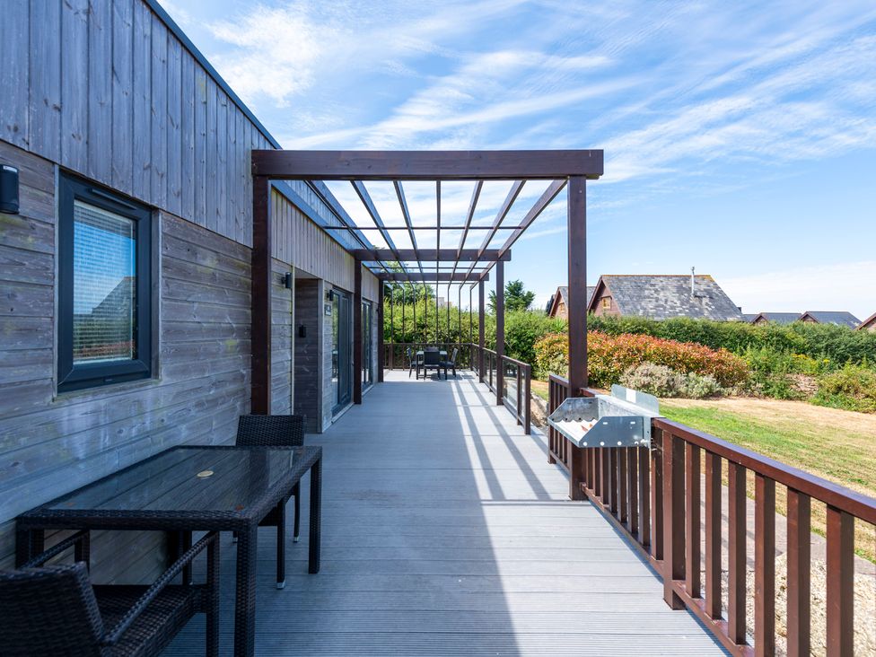 An outdoor deck with seating and a pergola at Barbara in Portreath
