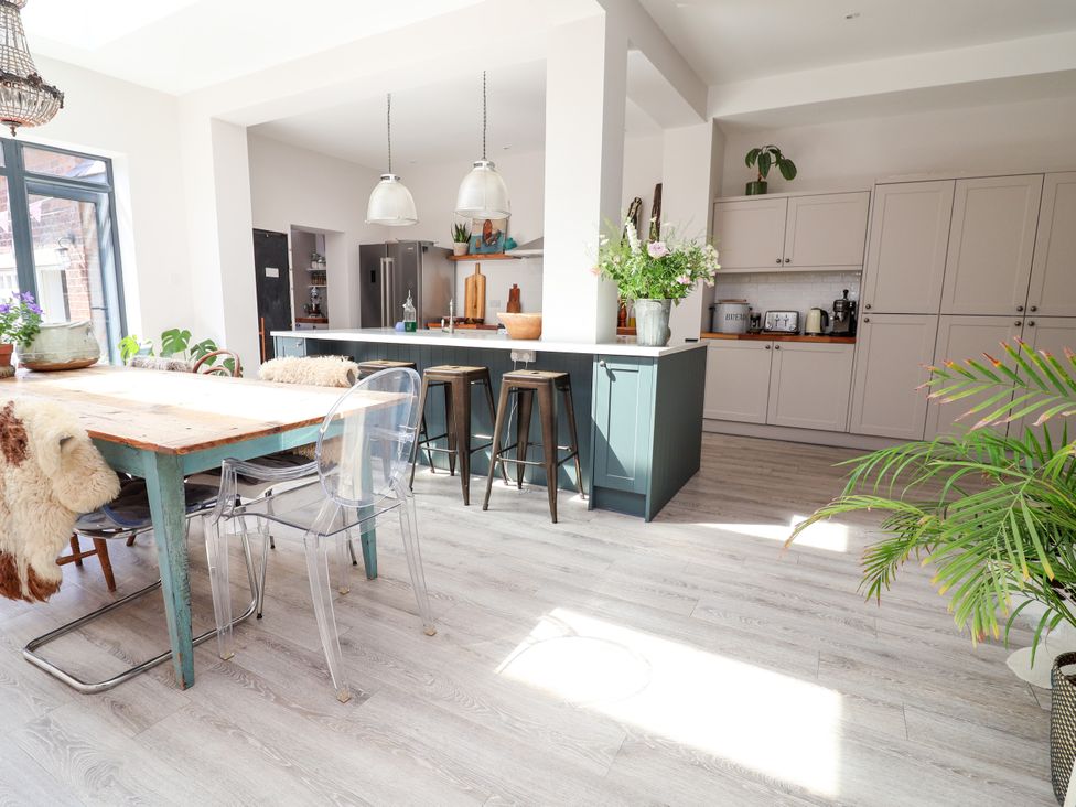 A kitchen with a dining table and bar stools at 34 Eaton Road Chester