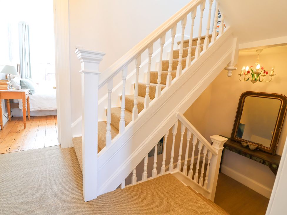 A staircase with a mirror and chandelier in the hallway at 34 Eaton Road Chester