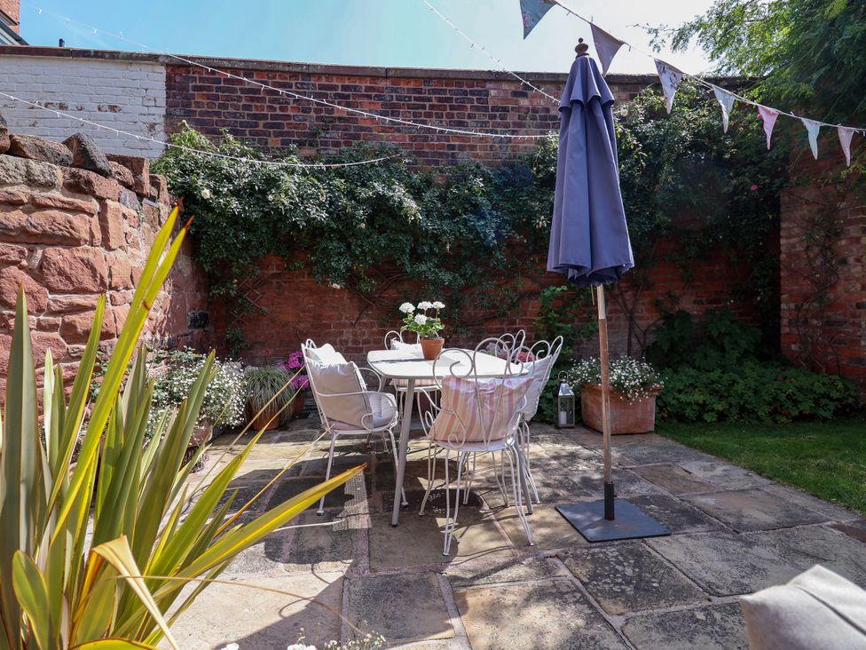 A garden with a table and chairs under an umbrella at 34 Eaton Road Chester