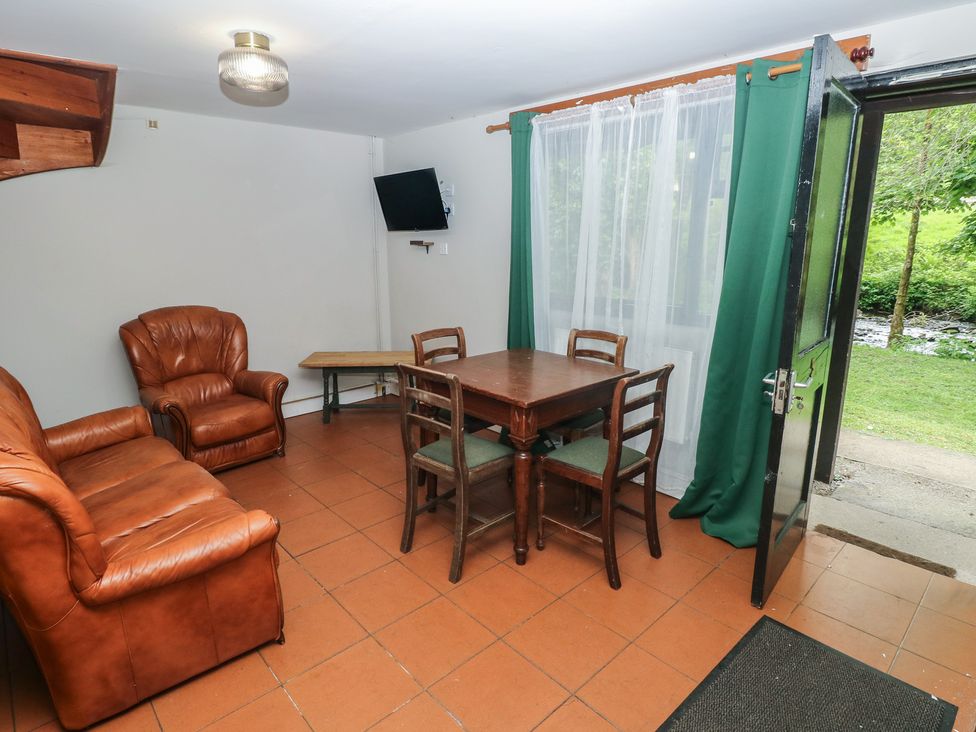 A dining room with an armchair and a table at Cabin No. 6 - Salt and Fern Cabins Goytre near Port Talbot