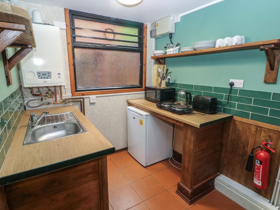 A kitchen with a sink, fridge and appliances at Cabin No. 6 - Salt and Fern Cabins Goytre near Port Talbot