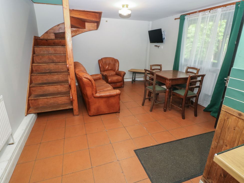 A living room with a staircase, sofa, dining table, and chairs at Cabin No. 6 - Salt and Fern Cabins Goytre near Port Talbot