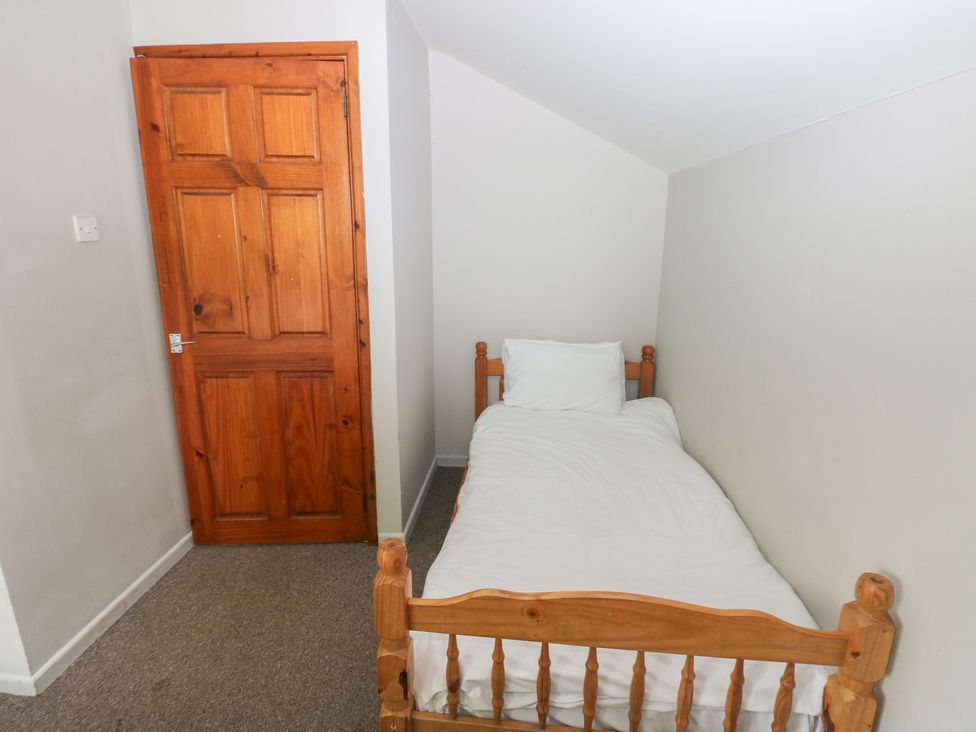 A bedroom with a single bed and wooden door at Cabin No. 6 - Salt and Fern Cabins Goytre near Port Talbot