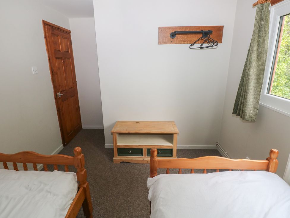 A bedroom with two beds and a wooden table at Cabin No. 6 - Salt and Fern Cabins Goytre near Port Talbot