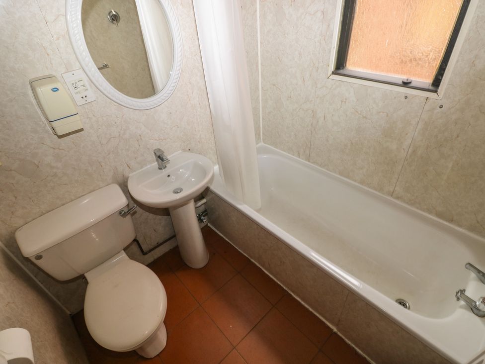 A bathroom with a toilet, sink, bathtub, and mirror at Cabin No. 6 - Salt and Fern Cabins Goytre near Port Talbot