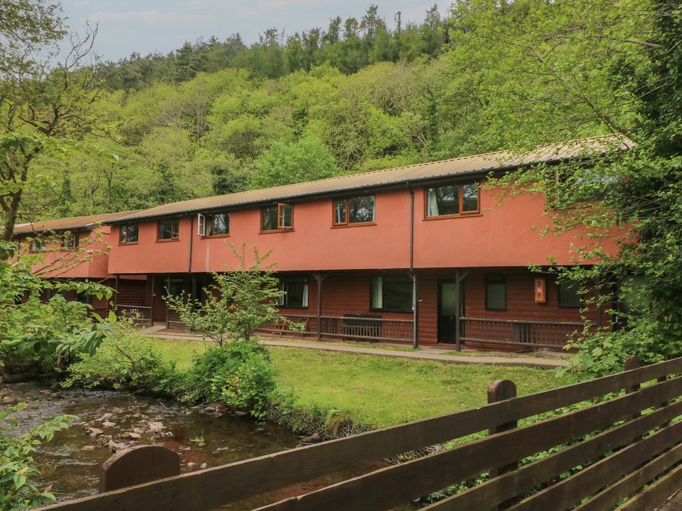 A building with windows and a door beside a stream at Cabin No. 6 - Salt and Fern Cabins Goytre near Port Talbot