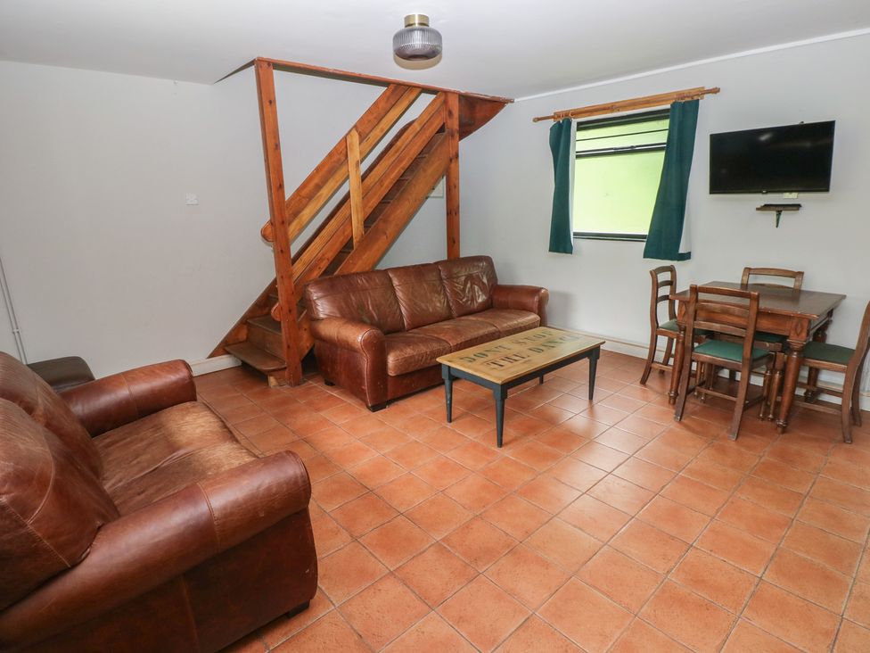 A living room with a sofa and dining area at Cabin No. 8 - Salt and Fern Cabins, Goytre near Port Talbot