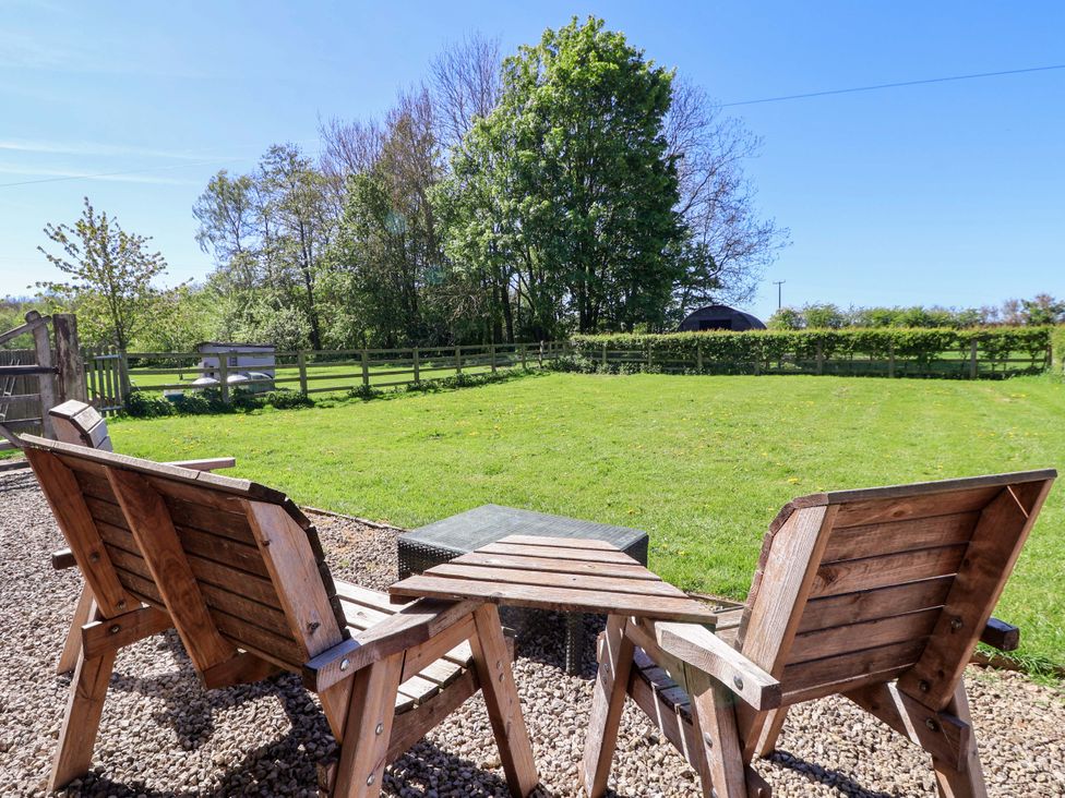 A garden with wooden chairs and a table at The Annexe at Dalby Carr