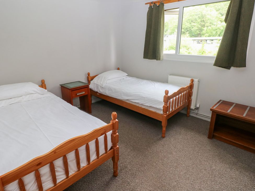A bedroom with two wooden beds and a window at Cabin No. 9 - Salt and Fern Cabins in Goytre near Port Talbot