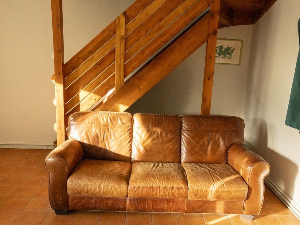 A living room with a leather couch and stairs at 3 bedroom Cabin (10 of 13) Port Talbot