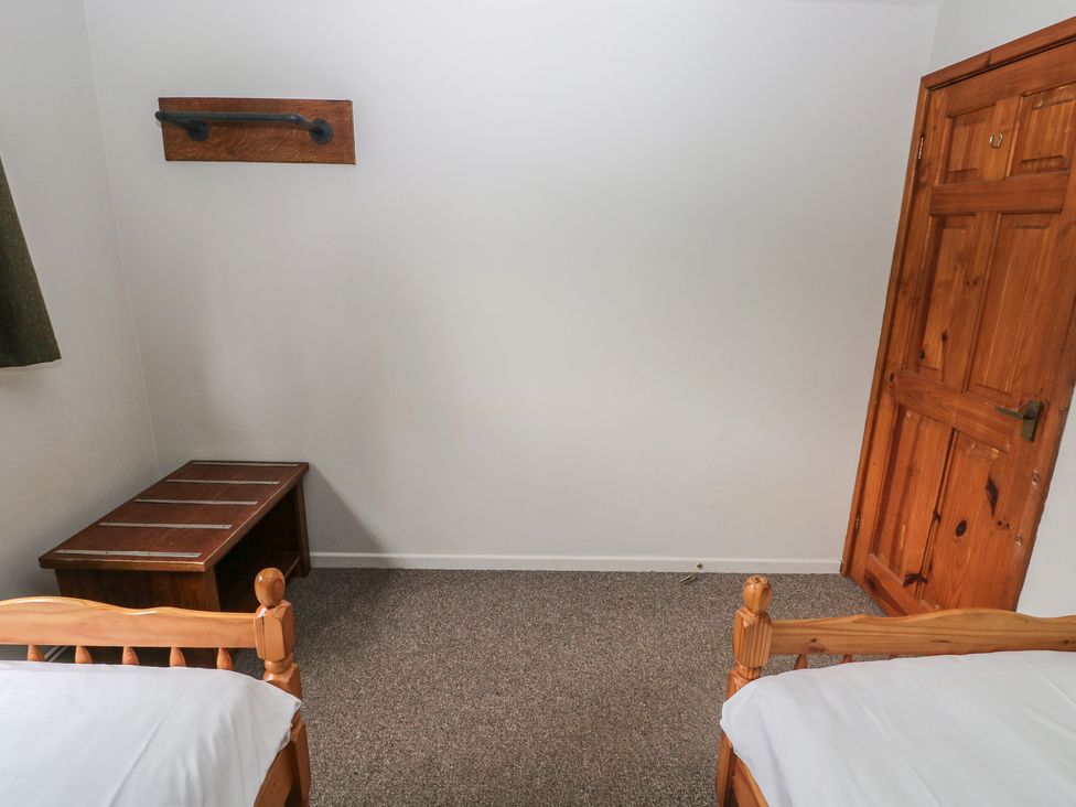 A bedroom with two beds and a wooden bench at Cabin No. 10 - Salt and Fern Cabins Goytre near Port Talbot