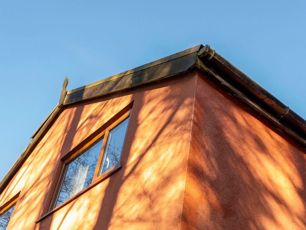 A close-up view of a house exterior with a roof and a window at 3 Bedroom Cabin (11 of 13) Port Talbot