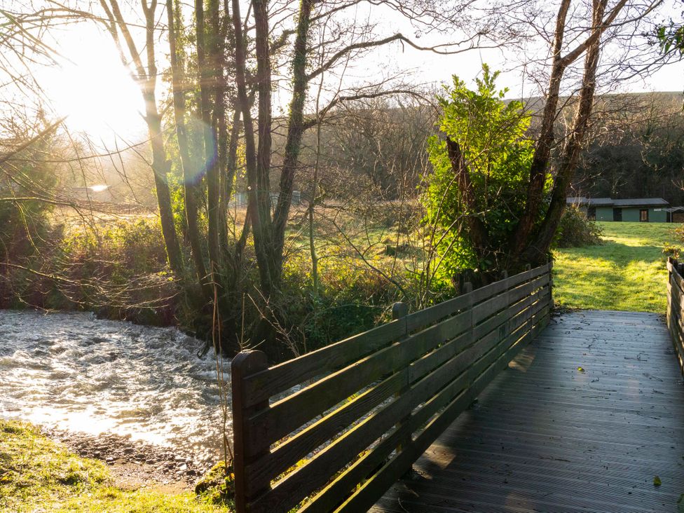 A bridge over a stream with trees and grass at 3 Bedroom Cabin (11 of 13) Port Talbot