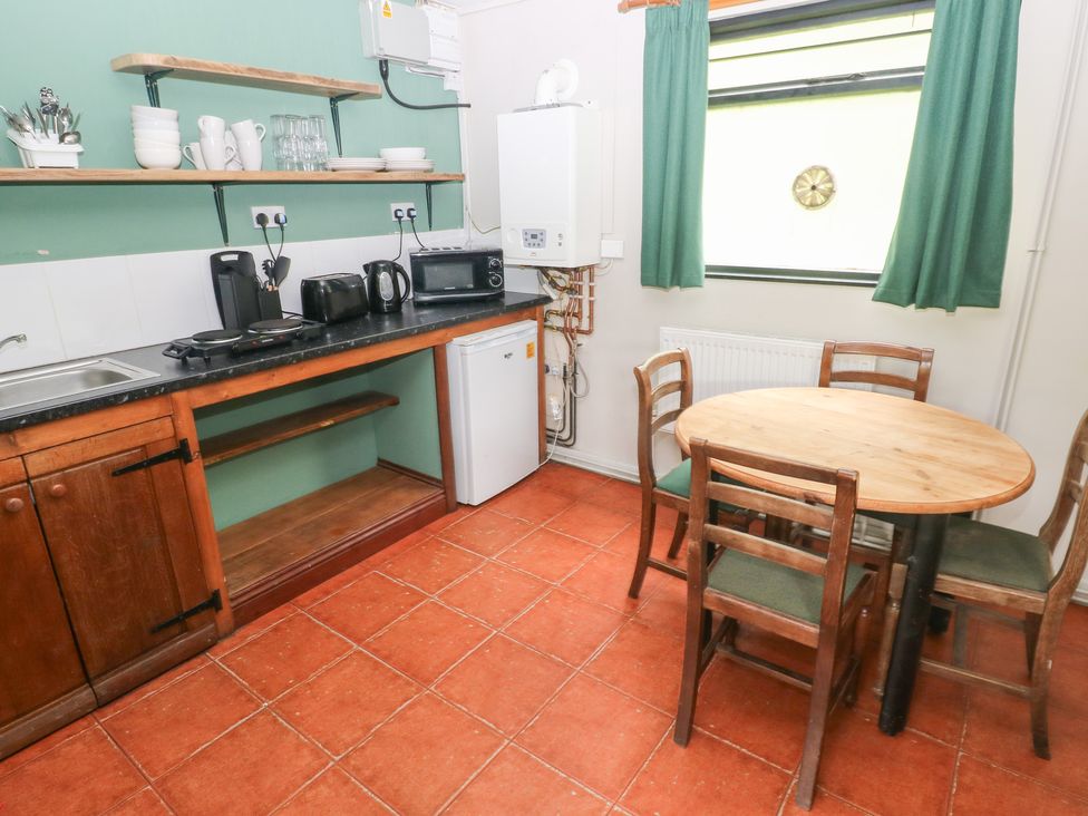 A kitchen with a sink, stove, and dining table at Cabin No. 11 - Salt and Fern Cabins, Goytre near Port Talbot