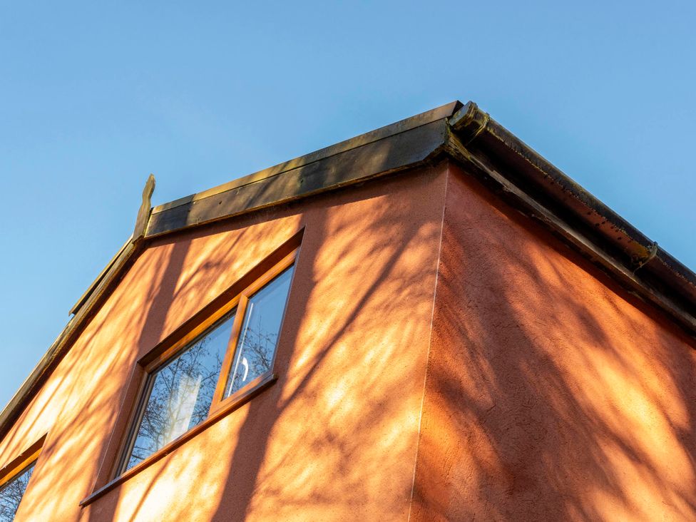 A corner of a building showing a roof and window