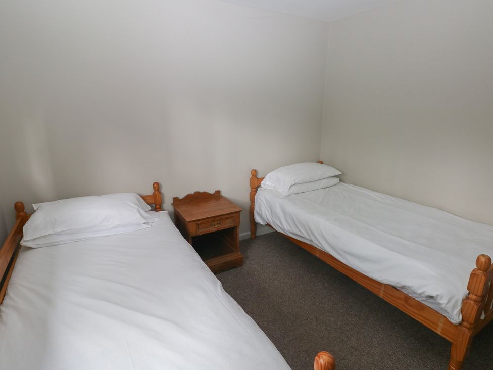 A bedroom with two single beds and a nightstand at Cabin No. 12 - Salt and Fern Cabins near Goytre near Port Talbot