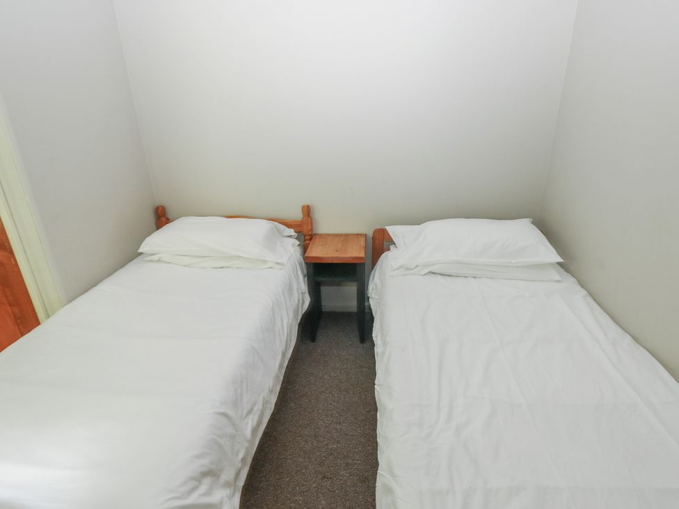 A bedroom with two single beds and a nightstand at Cabin No. 12 - Salt and Fern Cabins Goytre near Port Talbot