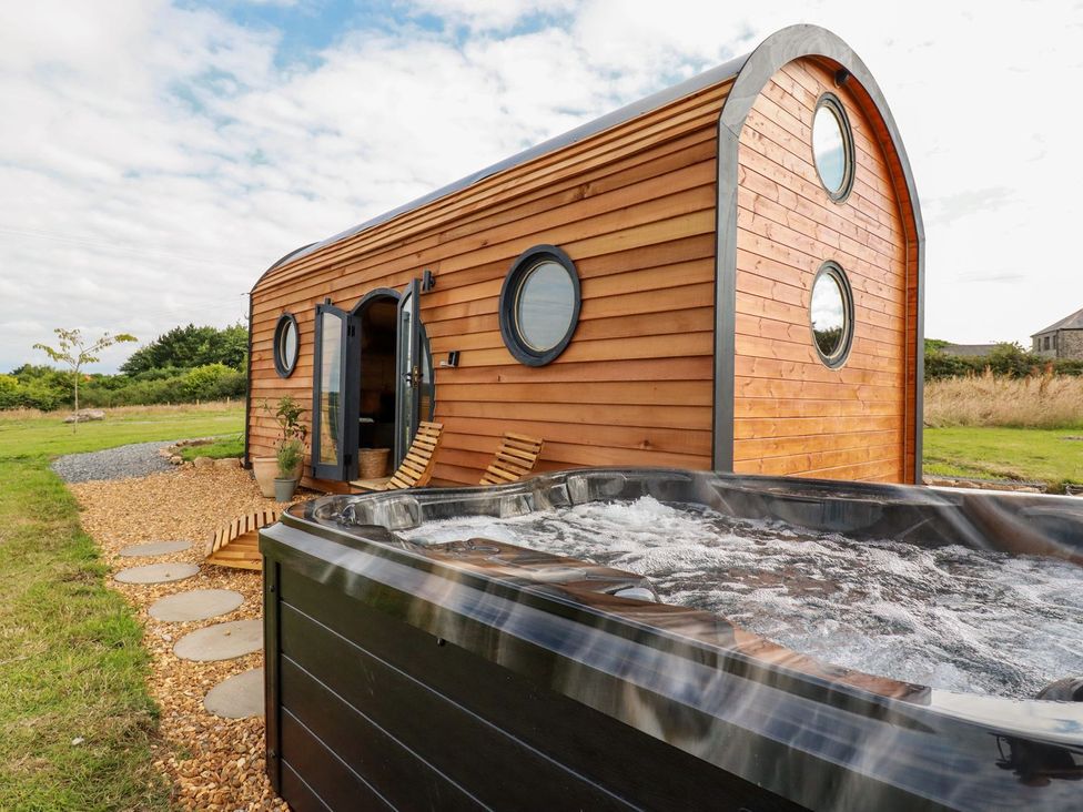 A wooden cabin with a hot tub in an outdoor area at The Olju in Truro