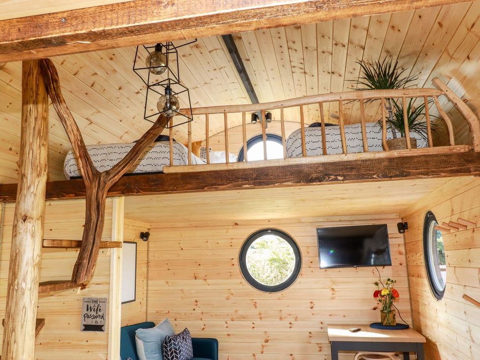 A living room with a loft bed and television at The Olju in Truro