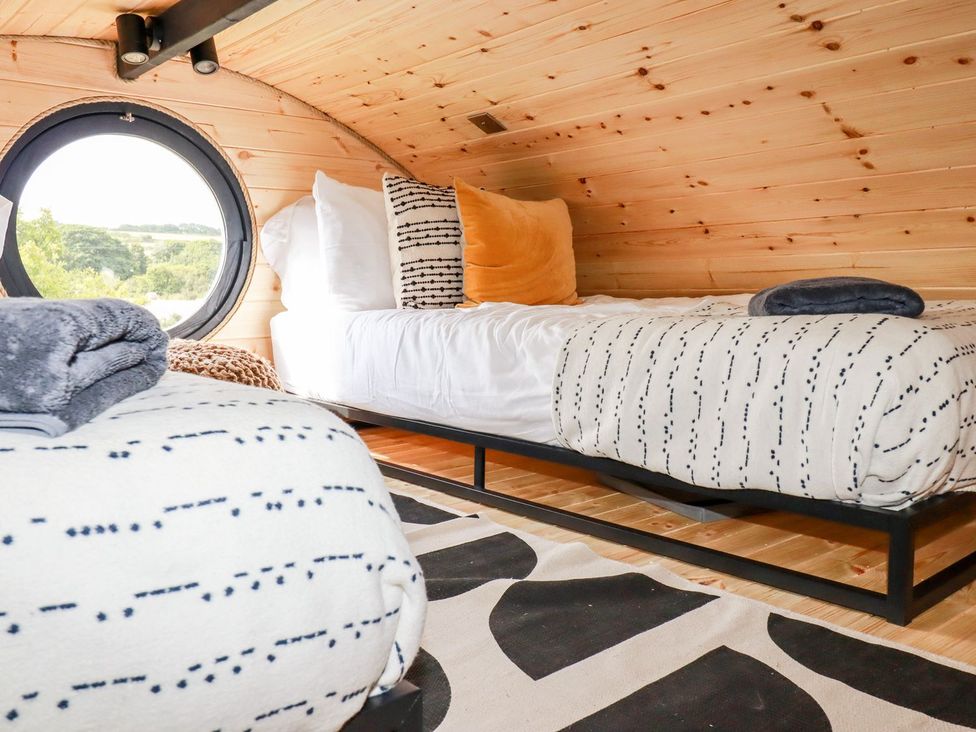 A bedroom with two beds and a round window at The Olju in Truro