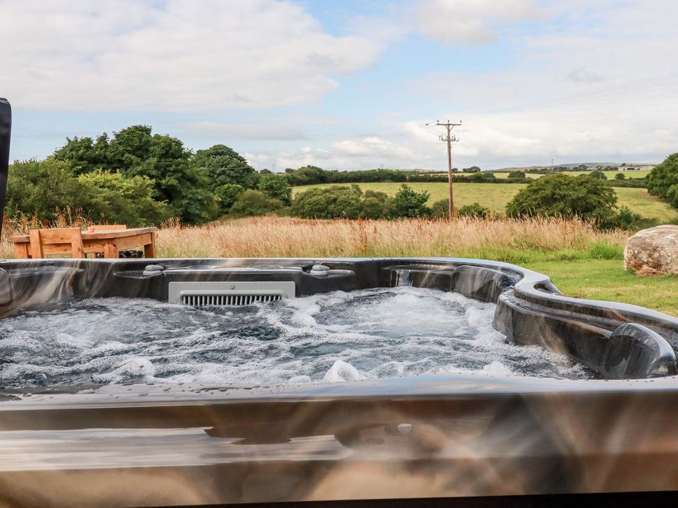 A hot tub with a view of a field at The Olju in Truro