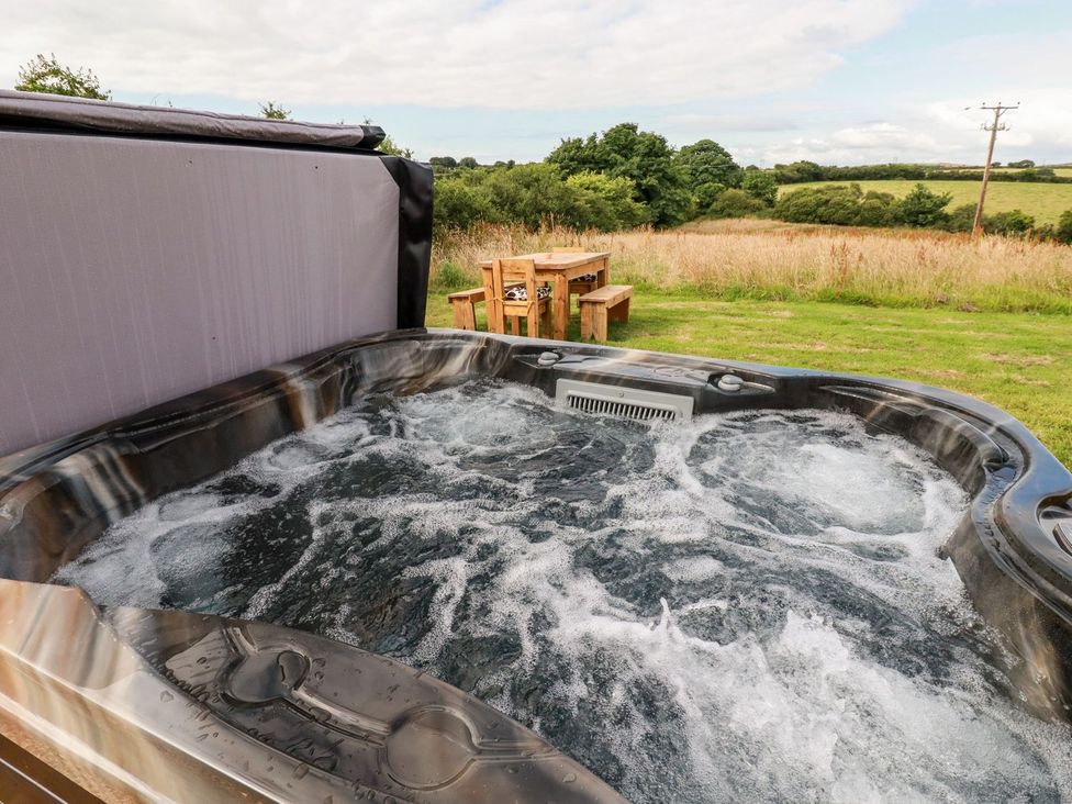 A hot tub with a wooden table in a field at The Olju in Truro