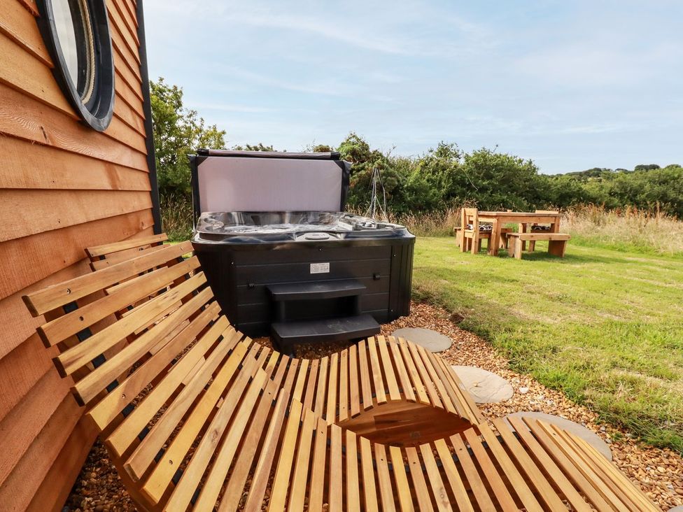 An outdoor area with a hot tub and wooden bench at The Olju in Truro