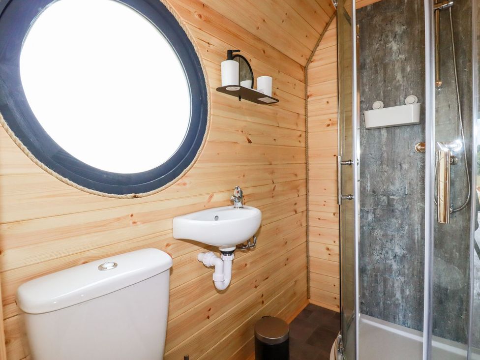 A bathroom with a sink, toilet, shower, and circular window at Stargaze in Truro