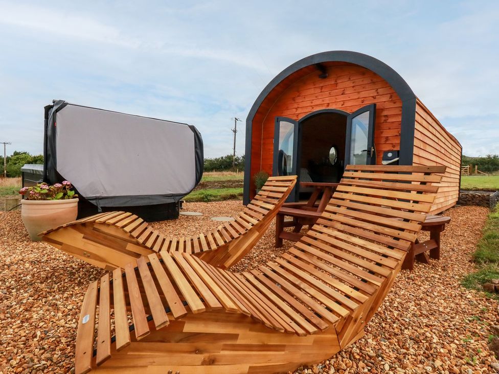 A cabin with wooden deck chairs and a potted plant at Stargaze in Truro