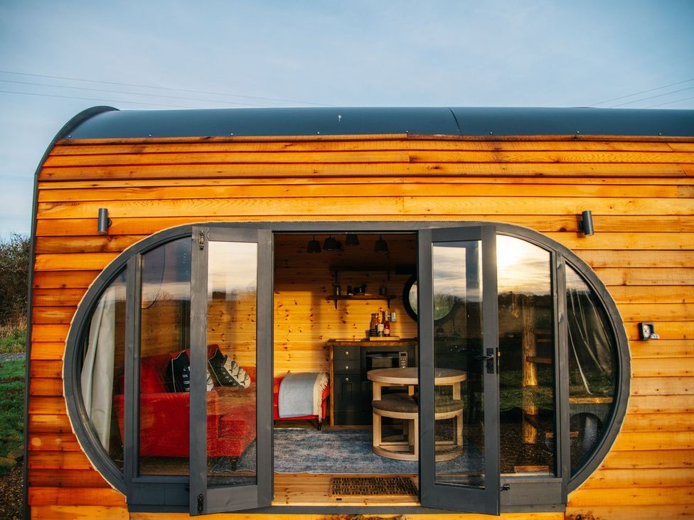 A living room with wooden features and a round window at The Palm in Truro