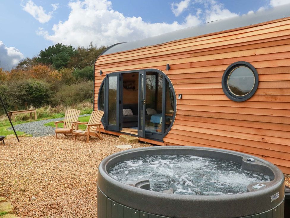 An outdoor area with a hot tub and wooden chairs at The Palm in Truro