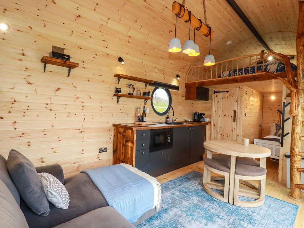 A living room with a sofa and kitchenette at The Palm in Truro