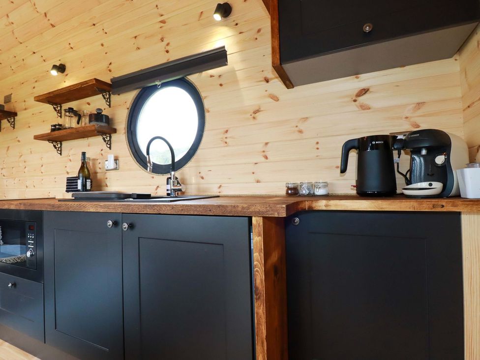 A kitchen with cabinets and a round window at The Palm in Truro