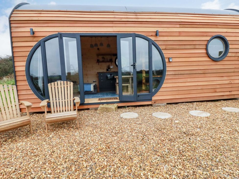 A wooden cabin with circular windows and patio chairs at The Palm in Truro