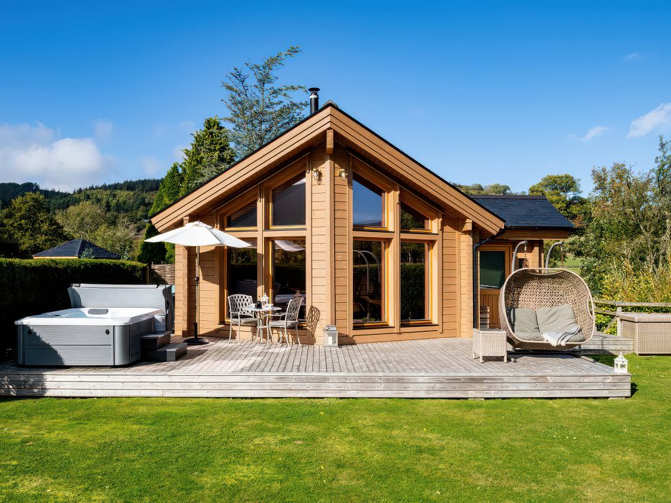 A garden with a hot tub and outdoor seating at Gezellig Log Cabin in Llandrillo
